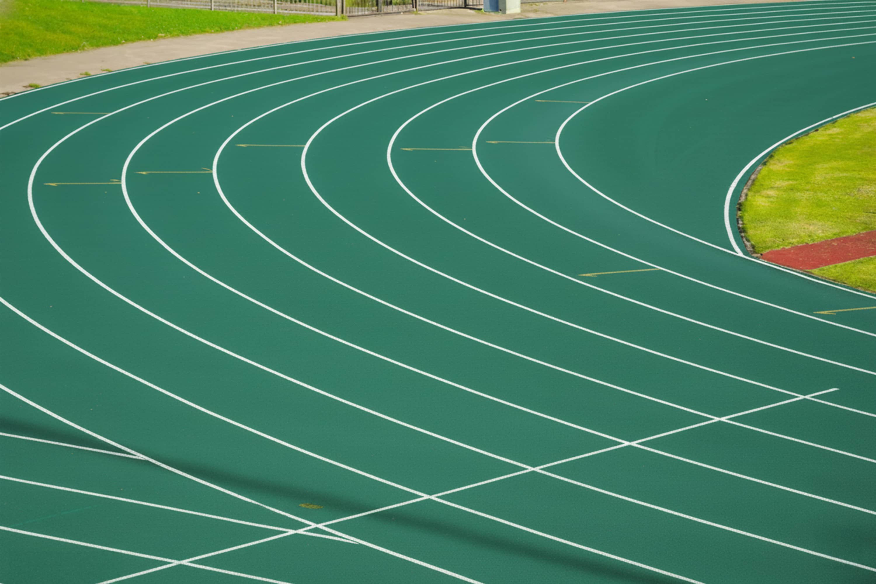 Curved lanes of a green athletics track.