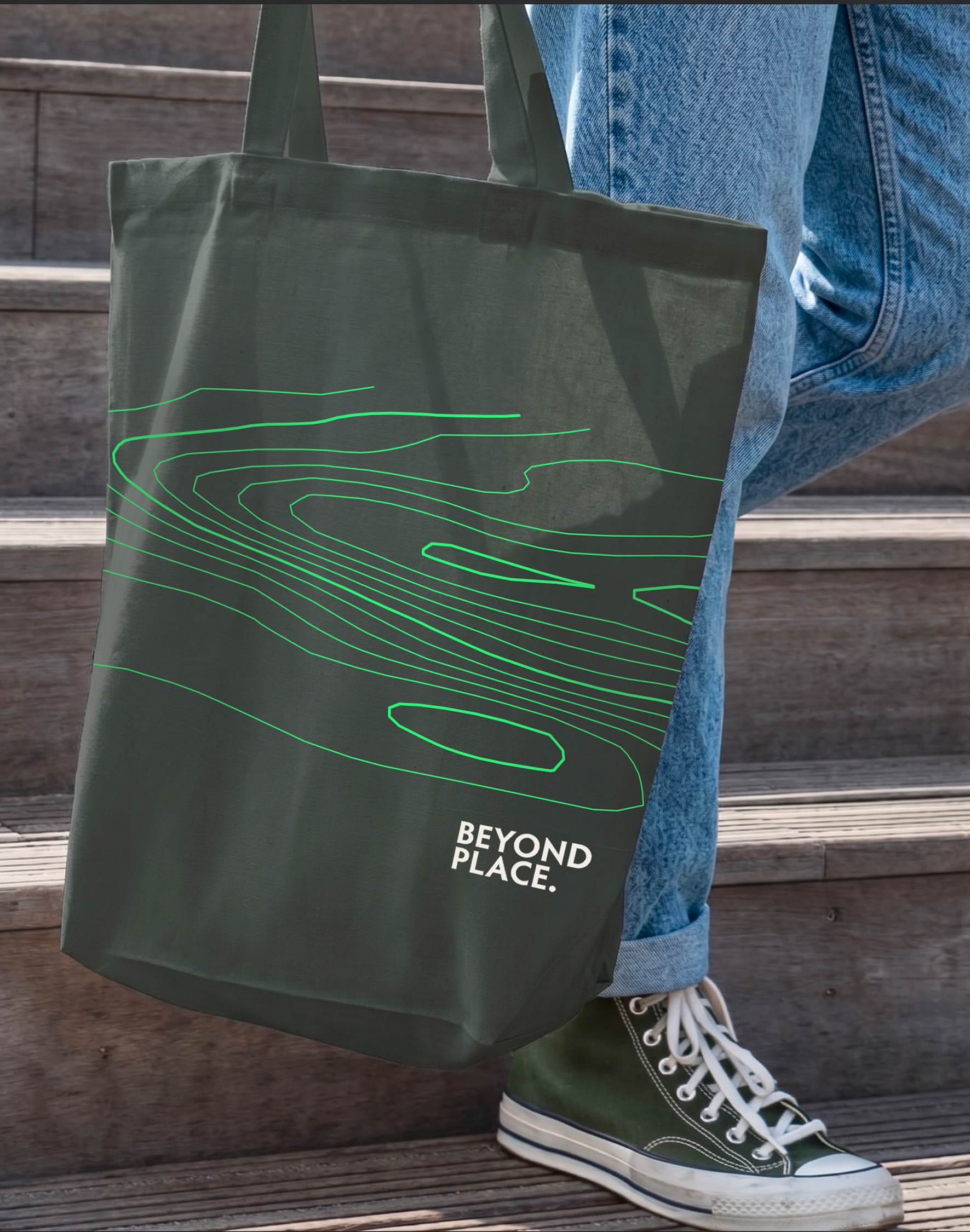 A dark green tote bag with the GummerLeathes contour-line design and “Beyond place” message.