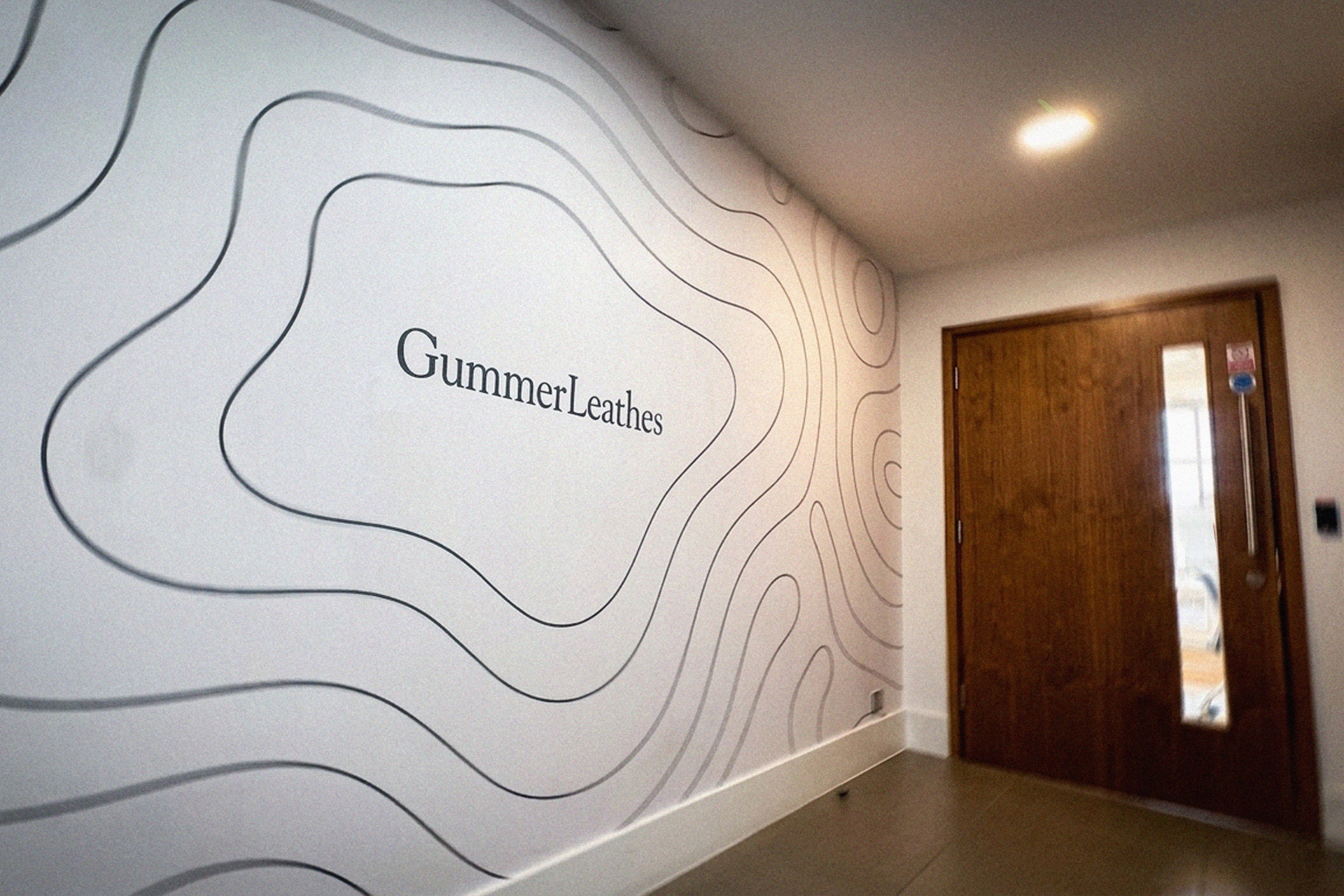 GummerLeathes wordmark and contour-line graphic on an office wall.