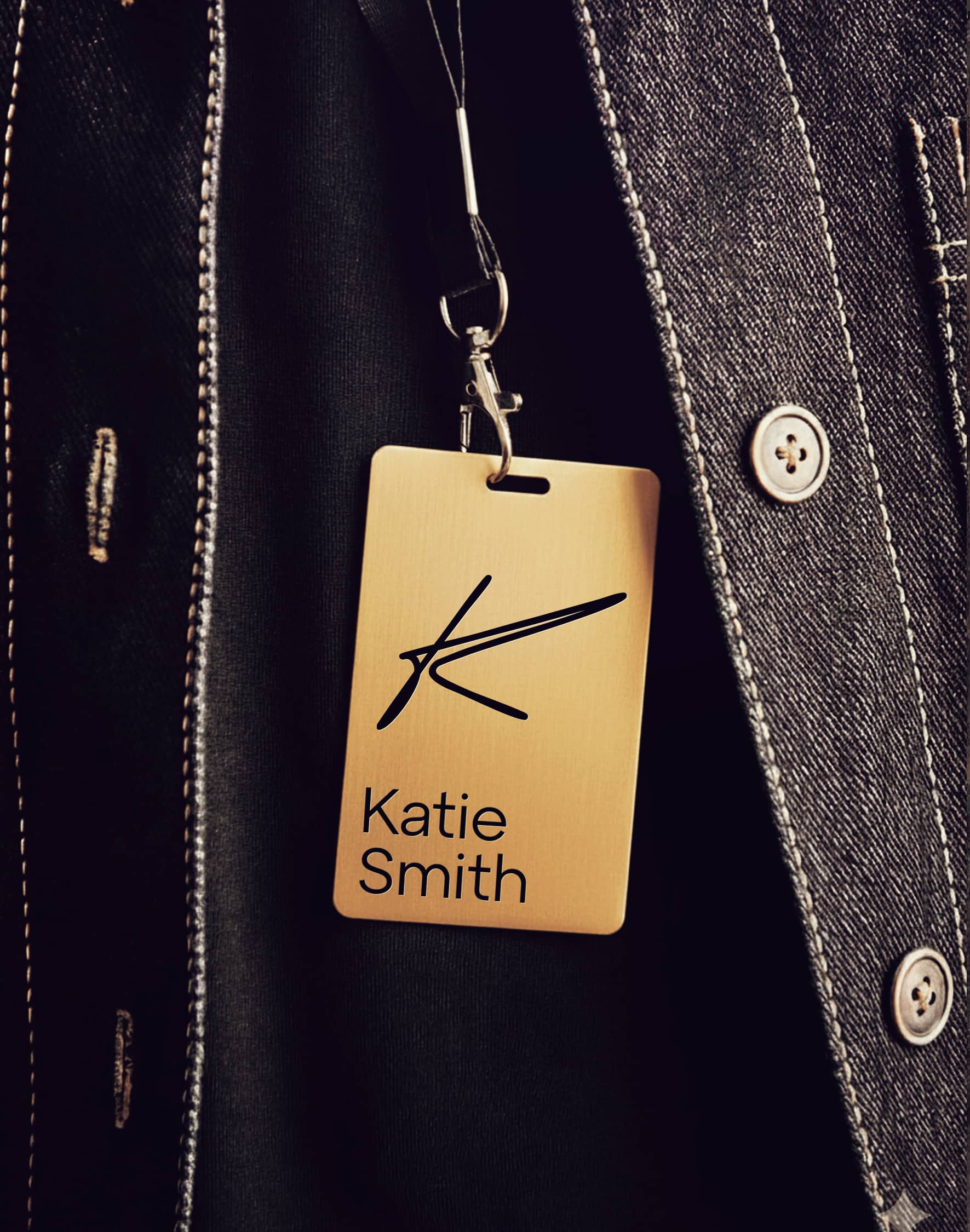 A gold Experiences by Katie name badge on a dark jacket.