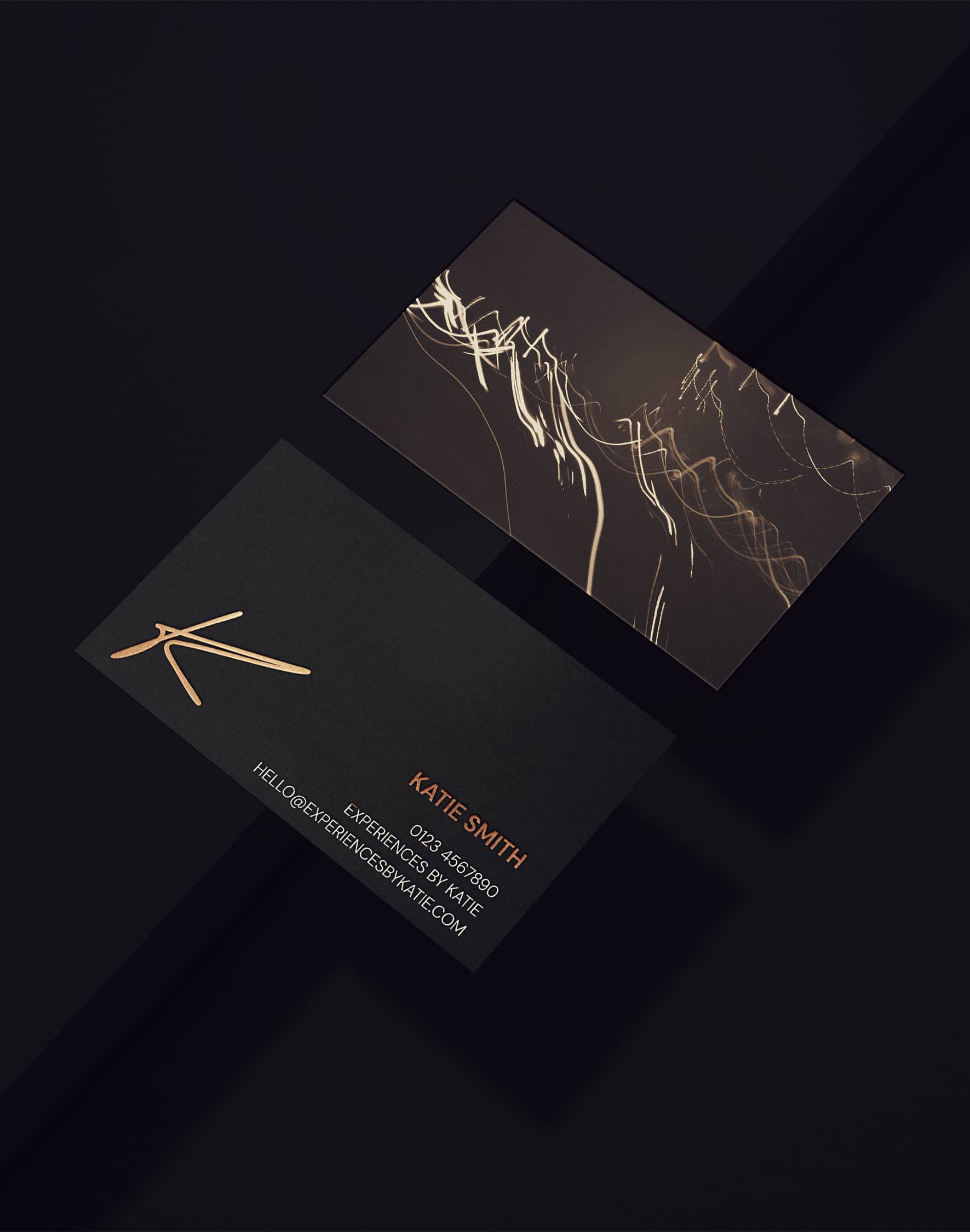 Experiences by Katie business cards with gold details on a dark background.
