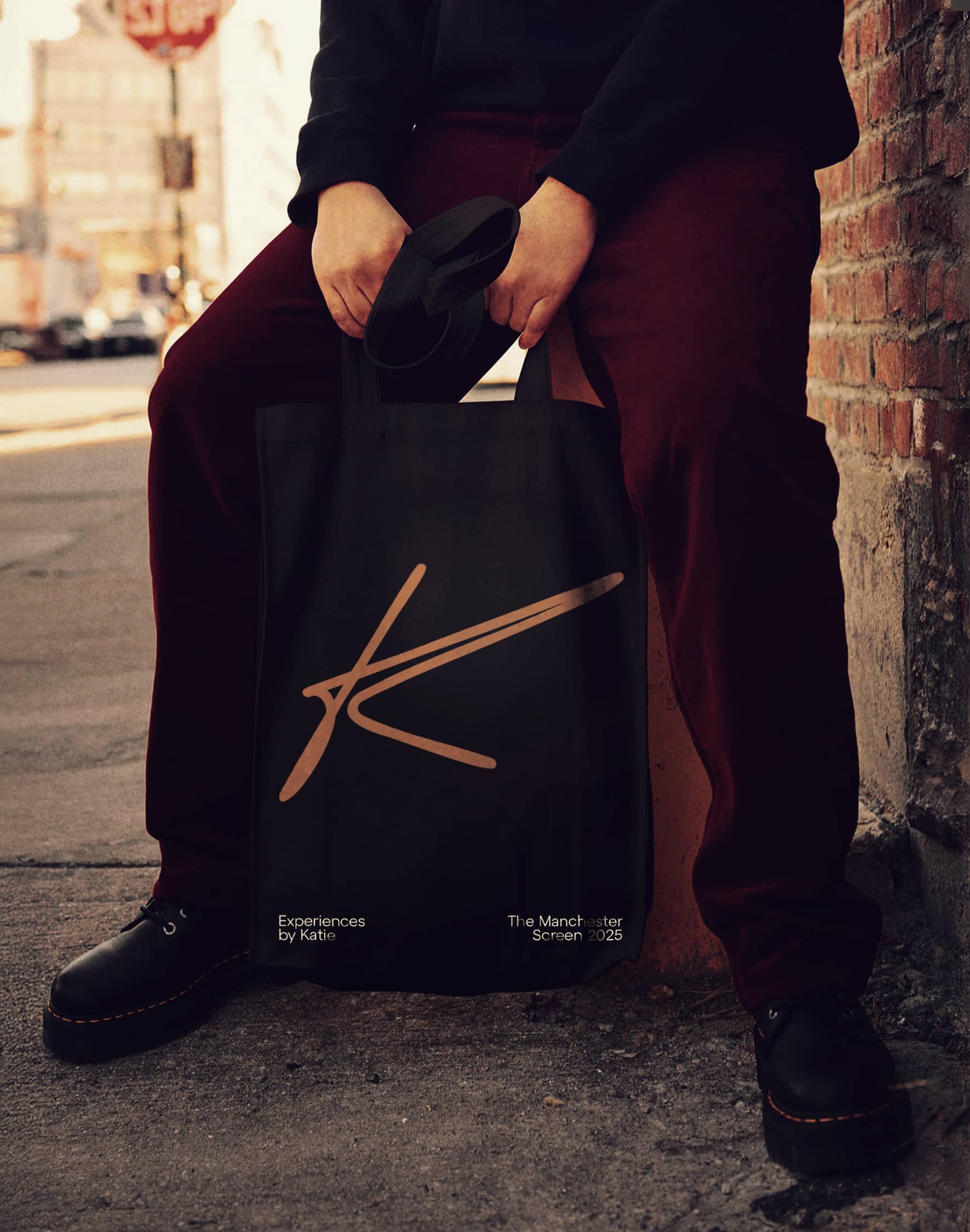 A black tote bag with the gold Experiences by Katie monogram.