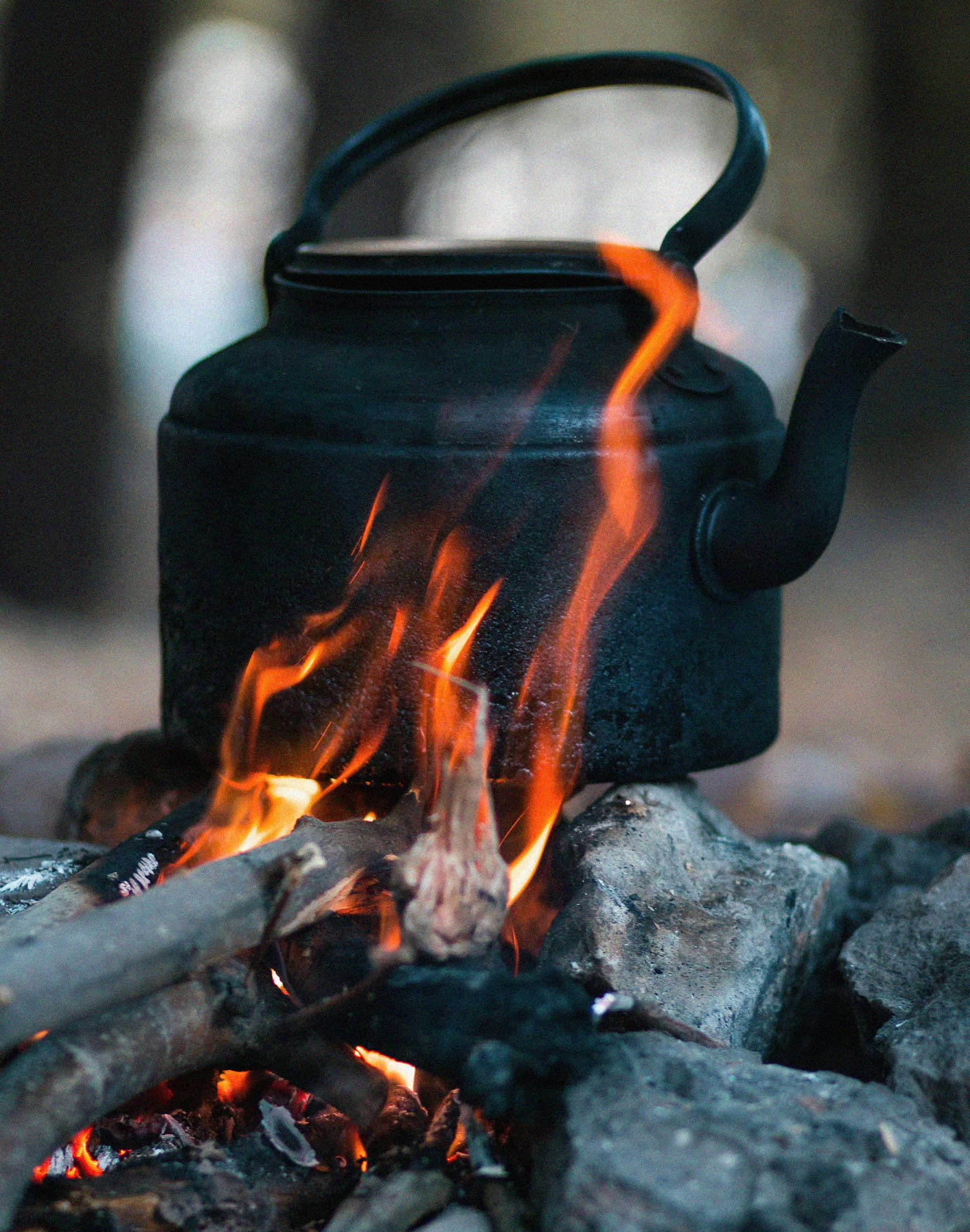 A camping kettle heating over a campfire.